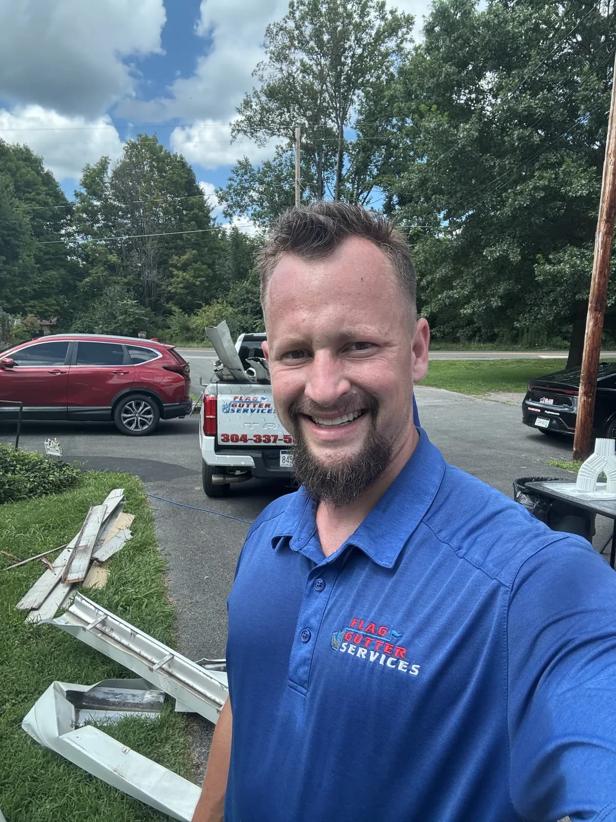 Christiaan, owner of Flag Gutter, on a job site with the work truck behind him