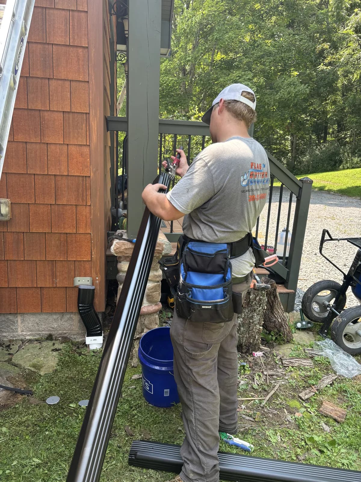 Dark bronze downspout fitted to a cedar-shake wall