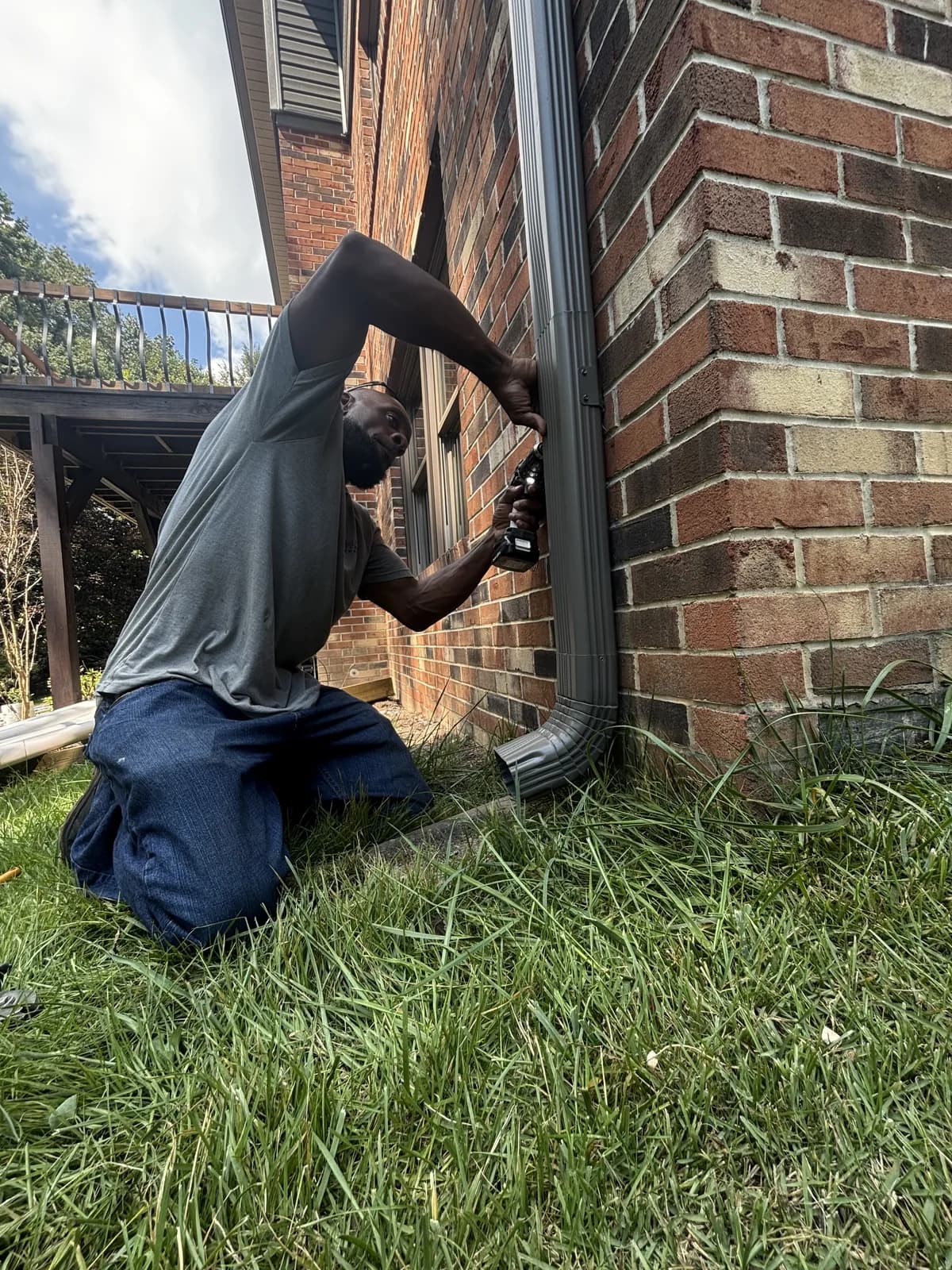 Flag Gutter crew member securing a downspout to a brick wall
