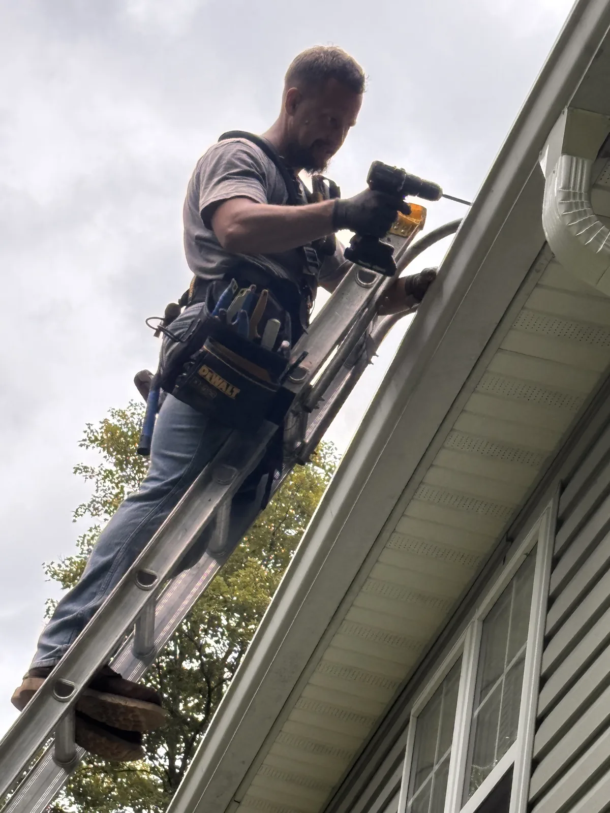 Flag Gutter installer fastening a seamless gutter run