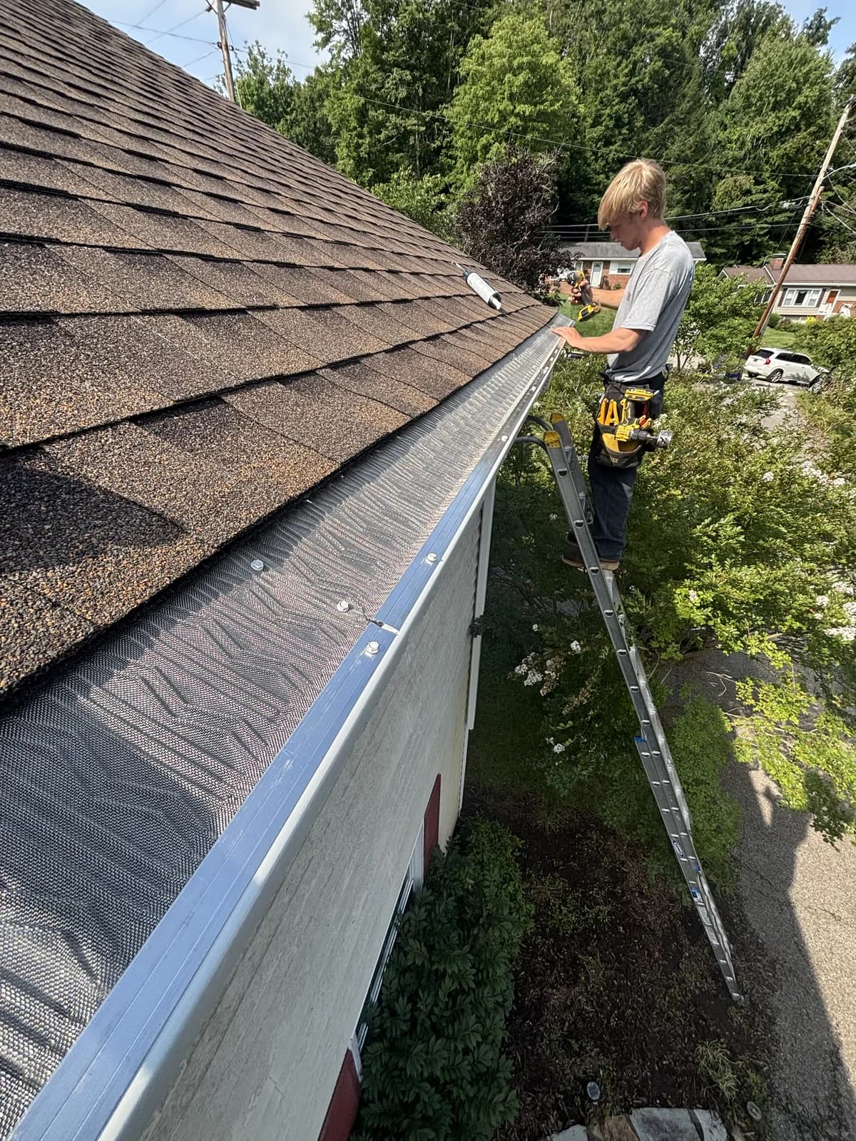 New seamless gutter hung along a brown shingle roofline